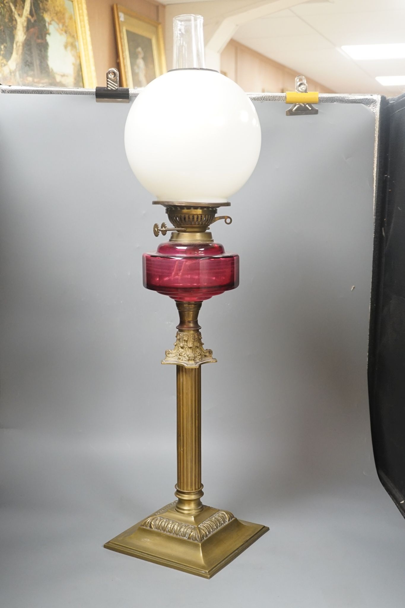 A Victorian brass and cranberry glass oil lamp, 78 cms high.